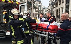 Firefighters carry an injured man on a stretcher in front of the offices of the French satirical newspaper Charlie Hebdo in Paris on January 7, 2015 (photo credit: AFP/ PHILIPPE DUPEYRAT)