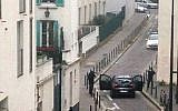 Armed gunmen face police officers near the offices of the French satirical newspaper Charlie Hebdo in Paris on January 7, 2015, during an attack on the offices of the newspaper which left 12 dead. (Photo credit: AFP/ ANNE GELBARD)