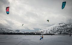 Israeli youths use kites to snowboard on a snow-covered field in the Golan Heights, January 8, 2015 (photo credit: Basal Awidat/Flash90)