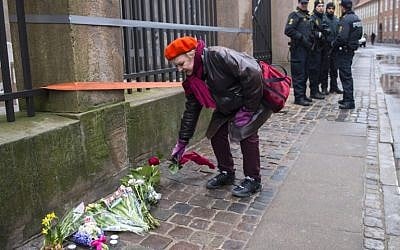 Heavily armed police officers watch a woman laying flowers outside the main synagogue in Copenhagen, Denmark, on February 15, 2015. (photo credit: AFP/Odd Andersen) Heavily armed police officers watch a woman laying flowers outside the main synagogue in Copenhagen, Denmark, on February 15, 2015. (photo credit: AFP/Odd Andersen)