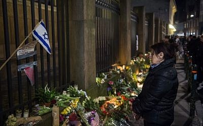 An Israeli flag flutters among flowers outside the main synagogue in Copenhagen, Denmark on February 15, 2015, hours after a fatal attack there. (photo credit: AFP/ODD ANDERSEN)