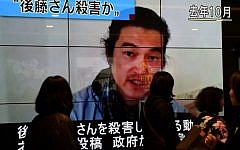 People walk past a big screen reporting that Kenji Goto was killed by the Islamic State in Tokyo on February 1, 2015. (photo credit: AFP PHOTO / Toru YAMANAKA)