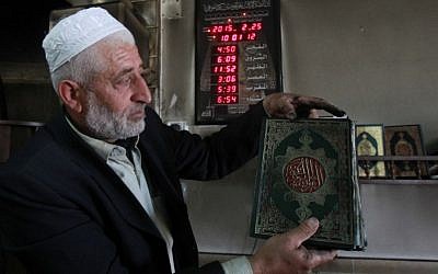 Palestinian Imam Ibrahim Abu Luha shows a burnt Koran, Islam's holy book, after a mosque was torched overnight in the West Bank village of al-Jaba, southwest of Bethlehem, February 25, 2015 .(photo credit: AFP/MUSA AL-SHAER) 