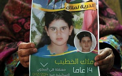 Khawla al-Khatib displays a poster on January 27, 2015, with a portrait of her 14-year-old daughter Malak, the youngest female Palestinian prisoner, whom Israel sentenced to two months in jail for trying to attack soldiers. (AFP/Abbas Moman)