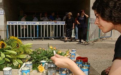 An unidentified Israeli woman lights candles at a memorial at the Hebrew University in Jerusalem Thursday August 1, 2002, a day after a bomb blew apart the university's Frank Sinatra International Students Center cafeteria, killing seven people, five of them Americans (AP Photo/Enric Marti)