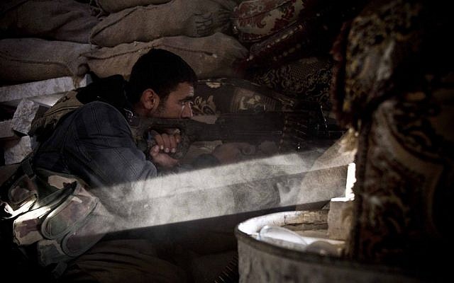 In this Tuesday, Nov. 23, 2014 photo, a Kurdish fighter fires on an Islamic State group position in Kobani, Syria (photo credit: AP/Jake Simkin) In this Tuesday, Nov. 23, 2014 photo, a Kurdish fighter fires on an Islamic State group position in Kobani, Syria (photo credit: AP/Jake Simkin)