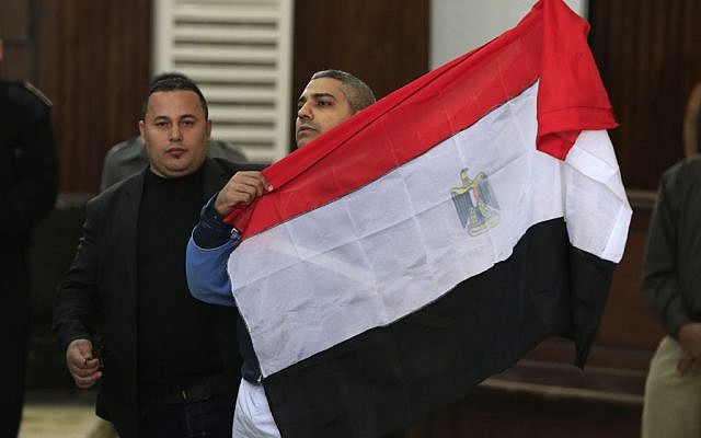 Mohammed Fahmy, a Canadian journalist of Al-Jazeera English, holds up an Egyptian flag after a retrial at a courthouse near Tora prison in Cairo, Egypt, Thursday, Feb. 12, 2015.  (photo credit: AP Photo/Hassan Ammar)