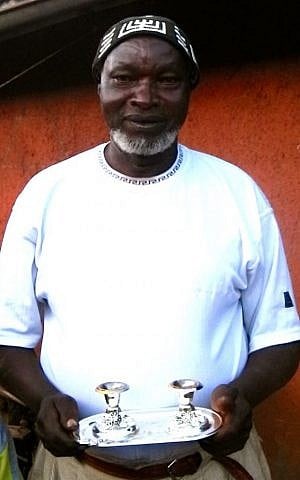 Avraham Ndungu Mbugua, one of the elders of the Messianic church who converted to Judaism, holds shabbat candles outside his home. (Melanie Lidman/Times of Israel)