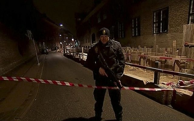 This image made from TV2 via Associated Press News video shows armed police guard behind police tape near a synagogue where police reported a shooting in downtown Copenhagen, Denmark, Sunday, Feb. 15, 2015. One person was shot in the head and two police officers were shot in the arms and legs, police said. (photo credit: AP Photo/TV2 via APTN) This image made from TV2 via Associated Press News video shows armed police guard behind police tape near a synagogue where police reported a shooting in downtown Copenhagen, Denmark, Sunday, Feb. 15, 2015. One person was shot in the head and two police officers were shot in the arms and legs, police said. (photo credit: AP Photo/TV2 via APTN)