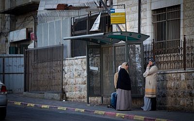 Palestinian women wait at a bus stop in the East Jerusalem neighborhood of Shuafat, on December 16, 2014 (photo credit: Miriam Alster/FLASH90)