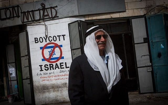 Illustrative: A Palestinian man walks by a graffiti sign calling to boycott Israel seen in the West Bank city of Bethlehem, February 11, 2015 (Miriam Alster/Flash90) Illustrative: A Palestinian man walks by a graffiti sign calling to boycott Israel seen in the West Bank city of Bethlehem, February 11, 2015 (Miriam Alster/Flash90)