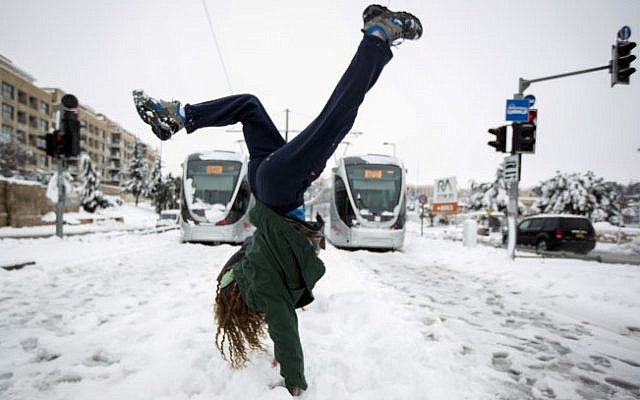 File: A young woman seen doing a hand stand on the lightrail tracks with the trains seen out of service behind her, on a snowy winter morning. February 20, 2015 (Photo credit: Muath Al Khatib/Flash90) File: A young woman seen doing a hand stand on the lightrail tracks with the trains seen out of service behind her, on a snowy winter morning. February 20, 2015 (Photo credit: Muath Al Khatib/Flash90)