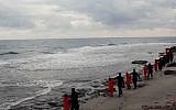 This image made from a video released February 15, 2015, by militants in Libya claiming loyalty to the Islamic State group purportedly shows Egyptian Coptic Christians in orange jumpsuits being led along a beach, each accompanied by a masked militant before the men are simultaneously beheaded. (AP Photo)