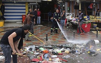 Municipality workers help clean up the site of a suicide bombing that targeted a street filled with hardware stores, killing over 20 people and wounding at least 45, Baghdad, Iraq, February. 7, 2015. (photo credit: AP/Karim Kadim) 