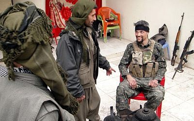 In this Thursday, Jan. 29, 2015 photo, Jordan Matson, 28, right, a former U.S. Army soldier, takes a break with other fighters from the main Kurdish militia, the People's Protection Units, or YPG, in Sinjar, Iraq. (Photo credit: AP/Vivian Salama)
