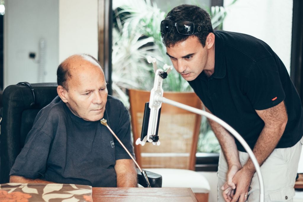 Sorin Hershko, who was injured in the raid on Entebbe in 1976, using the Sesame phone with Sesame Enable CEO Oded Ben Dov. (Basti Hansen/JTA)