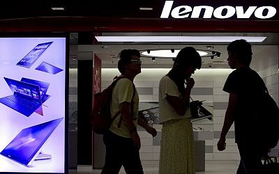 In this Aug. 15, 2013 file photo, people walk past a Lenovo flagship experience store in Beijing, China. (photo credit: AP/Andy Wong, File)