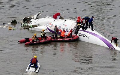 Emergency personnel approach a commercial plane after it crashed in Taipei, Taiwan, Wednesday, Feb. 4, 2015. (photo credit: AP Photo)