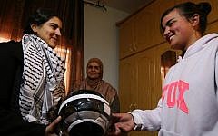 A friend offers a football to Malak al-Khatib (left), a 14-year-old Palestinian schoolgirl who was jailed in an Israeli prison for six weeks, at her home in the West Bank village of Beitin after she was released the previous day on February 14, 2015. (AFP/Abbas Momani)