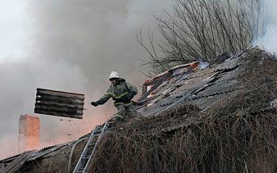 A firefighter dismantles a roof to extinguish a building on fire after shelling between Russian-backed separatists and the Ukrainian government in Artemivsk, Ukraine, February 14, 2015. (photo credit: AP/Petr David Josek)