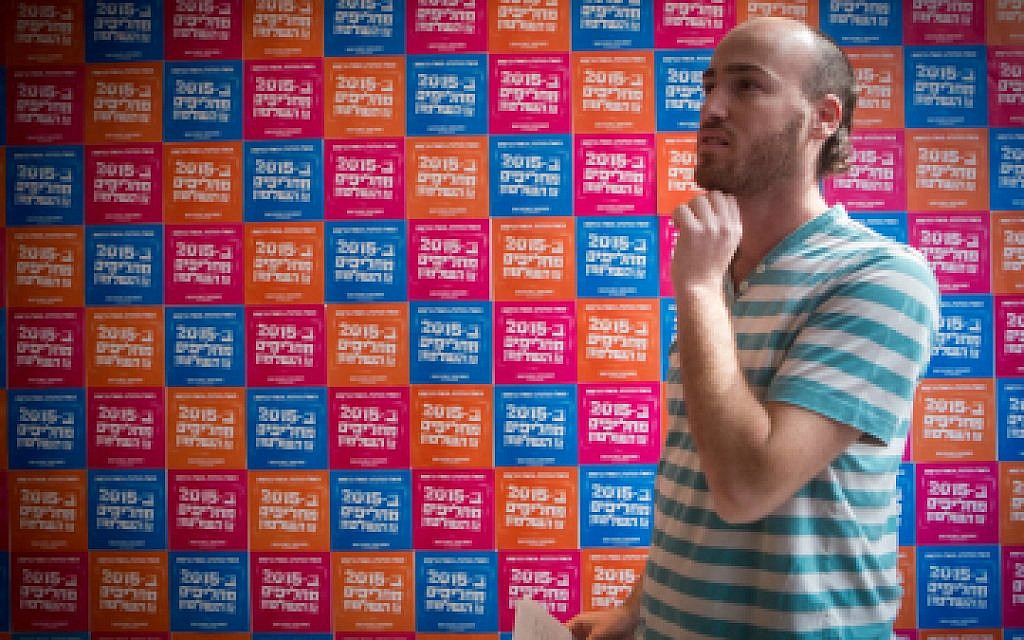 A V15 activist standing in front of posters calling for a change of government in Jerusalem on February 09, 2015. (photo credit: Miriam Alster/FLASH90)