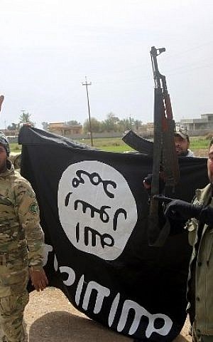 Members of the Iraqi paramilitary Popular Mobilization units celebrate with a flag of the Islamic State (IS) group after retaking the village of Albu Ajil, near the city of Tikrit, from the jihadist group, on March 9, 2015. (photo credit: AFP/Ahmad al-Rubaye)