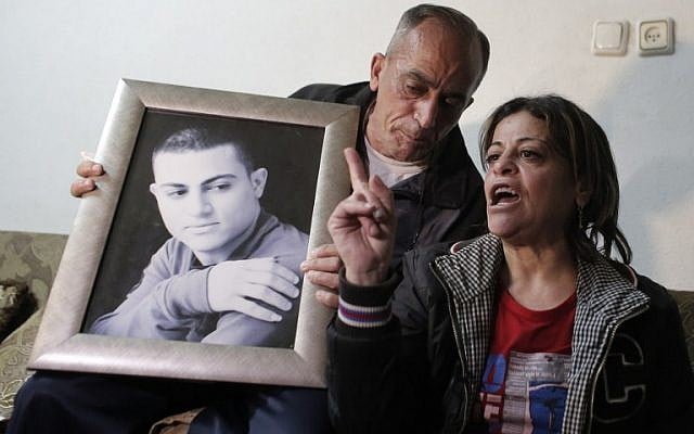The parents of Muhammed Musallam  hold a portrait of their son,  March 10, 2015, (photo credit: AFP/AHMAD GHARABLI)