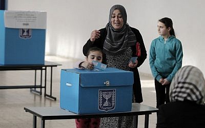 An Arab Israeli girl casts her mother's ballot at a polling station in the northern Israeli town of Umm al-Fahm on March 17, 2015. (photo credit: AFP / AHMAD GHARABLI) An Arab Israeli girl casts her mother's ballot at a polling station in the northern Israeli town of Umm al-Fahm on March 17, 2015. (photo credit: AFP / AHMAD GHARABLI)