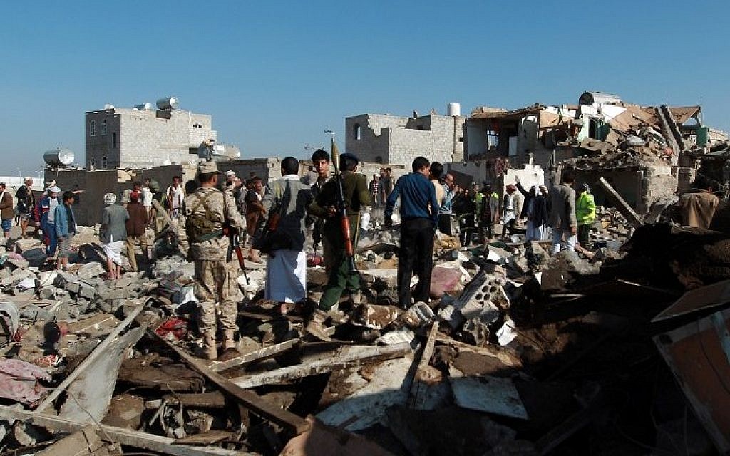 Yemeni Houthi rebels and members of the security forces loyal to the Shiite movement inspect the damage at the scene of a Saudi airstrike targeting the group, which controls Sanaa near the airport in the Yemeni capital, on March 26, 2015. (photo credit: Mohammed Huwais/AFP)