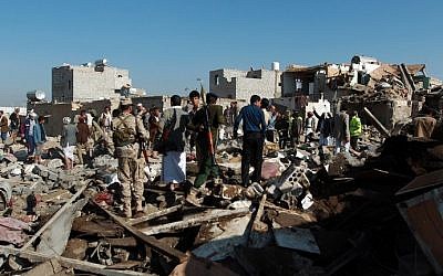 Yemeni Houthi rebels and members of the security forces loyal to the Shiite movement inspect the damage at the scene of a Saudi airstrike targeting the group, which controls Sanaa near the airport in the Yemeni capital, on March 26, 2015. (photo credit: Mohammed Huwais/AFP)