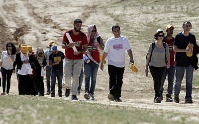 Joint List head Ayman Odeh, in white shirt, and Israeli left-wing MP Dov Khenin, on right, march alongside several dozen protesters in the Bedouin village of Wadi al-Naam on March 26, 2015. (AFP/AHMAD GHARABLI)