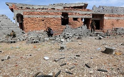 Iraqi security forces rest next to a damaged house in the southern entrance of the city of Tikrit , Iraq, March 29, 2015. (photo credit: AFP/AHMAD AL-RUBAYE) 