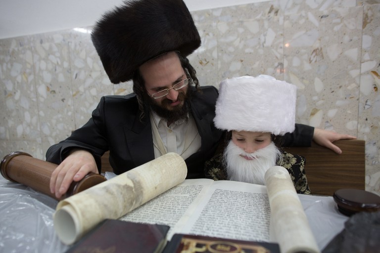 An ultra-Orthodox Jewish man and his dressed-up child read the book of Esther at a synagogue in the Israeli city of Bnei Brak on March 4, 2015. (photo credit: AFP PHOTO / MENAHEM KAHANA) An ultra-Orthodox Jewish man and his dressed-up child read the book of Esther at a synagogue in the Israeli city of Bnei Brak on March 4, 2015. (photo credit: AFP PHOTO / MENAHEM KAHANA)