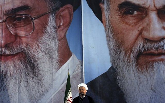 Iranian President Hassan Rouhani makes an address in front of portraits of the supreme leader Ayatollah Ali Khamenei, left, and Ayatollah Khomeini, the founder of the Islamic Republic, during a ceremony marking the 25th anniversary of Khomeini's death, at his shrine just outside Tehran, June 3, 2014. (photo credit: AP Photo/Vahid Salemi)