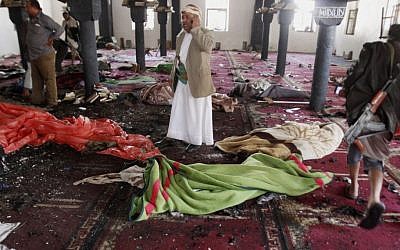 People stand amid bodies covered with blankets in a mosque after a suicide attack during the noon prayer in Sana'a, Yemen, on March 20, 2015. (photo credit: AP/Hani Mohammed)
