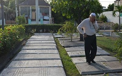 Jewish community leader Ainsley Henriques walks on historic gravestones engraved with Hebrew inscriptions outside Jamaica's last synagogue, the Sha’are Shalom, in Kingston on Feb. 27, 2015. “Regardless of what happens in the future, I want people to always know that Jews were indeed here,” said Henriques. (Photo credit: David McFadden/AP Photo)