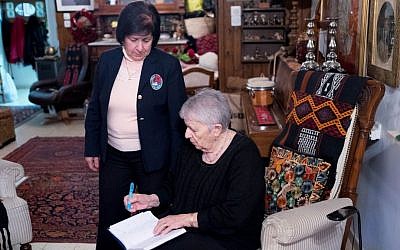 Najla and Yael log sales in Yael's sitting room in Jerusalem (photo credit: Shaina Shealy/Times of Israel)