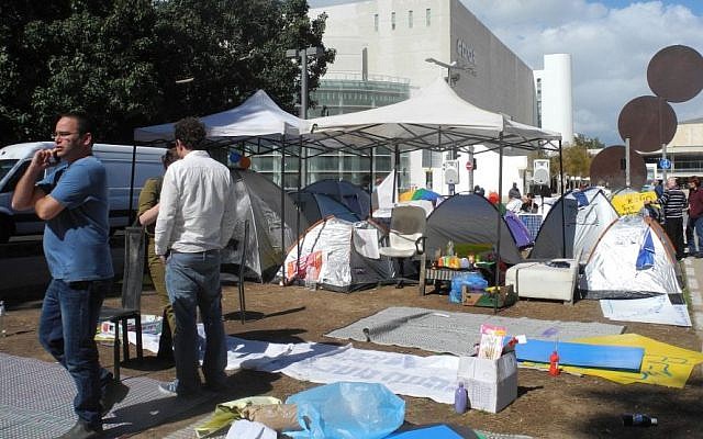 Shay Cohen, in the blue t-shirt, and Itamar Pirchi, in the while shirt, speak with reporters next to their tent protest on Monday. (Melanie Lidman/Times of Israel)