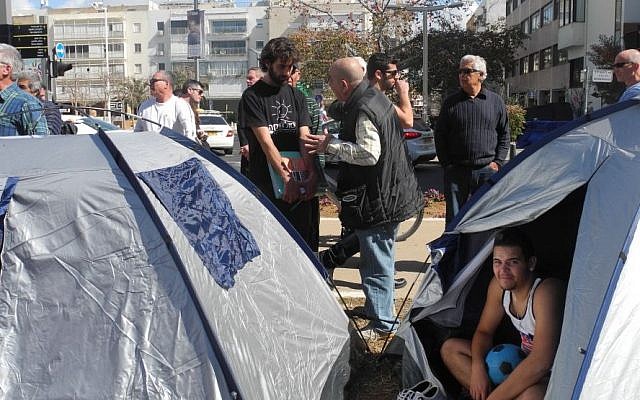 GGavriel Vinegrad, standing in the black T-shirt, debates with a passerby at a tent protest on Rothschild Boulevard on Monday. March 2. (Melanie Lidman/Times of Israel)