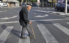 Illustrative: An elderly man crosses the street in Tel Aviv, May 20, 2009. (Serge Attal/Flash90)