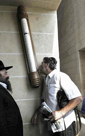 An Israeli man kisses a large mezuzah at the Ben Gurion airport, outside Tel Aviv, on Sep 2, 2010 (photo credit: Yossi Zelige/Flash90)