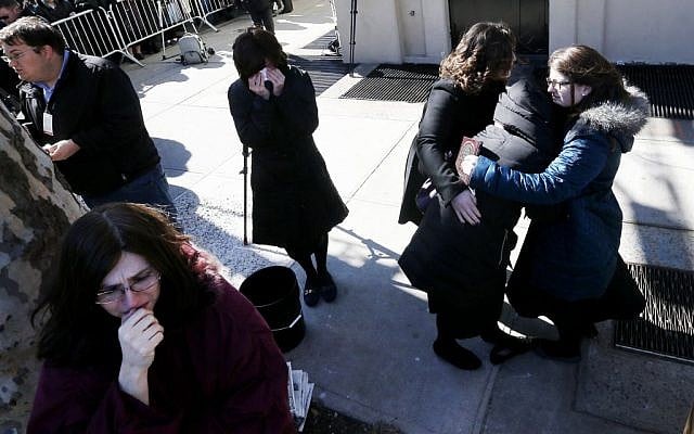 A woman is consoled as others cry as vehicles carrying the remains of the seven siblings killed in a house fire depart after funeral services, Sunday, March 22, 2015, in the Brooklyn borough of New York. (photo credit: AP/Julio Cortez)