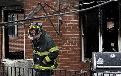 An FDNY firefighter looks over the scene of a deadly house fire that killed seven siblings in the Brooklyn borough of New York, March 21, 2015. (photo credit: AP/Craig Ruttle)