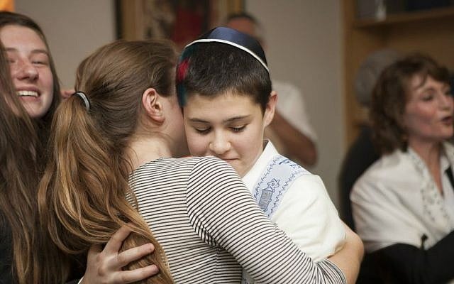 Tom Chai Sosnik is hugged by a classmate following ceremony at Tehiyah Day School marking his transitioning from female to male, March 13, 2015.(photo credit: Misha Bruk, BrukStudios.com)