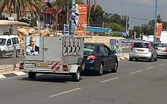 A truck with placards bearing the image of Likud party leader Prime Minister Benjamin Netanyahu drives down a street in the southern city of Sderot (photo credit: Ilan Ben Zion/Times of Israel)