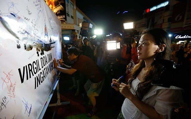 Kelly Wen, wife of a Chinese passenger aboard the missing Malaysia Airlines flight MH370 looks at an MAS airplane poster during an event to mark the one-year anniversary of the plane's disappearance, in Kuala Lumpur, Malaysia, on Friday, March 6, 2015. (AP/Vincent Thian)