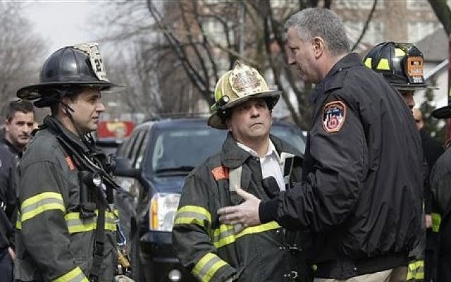 New York City Mayor Bill de Blasio, right, speaks to firefighters who responded to a fatal fire in the Brooklyn borough of New York, Saturday, March 21, 2015. The fire raged through the residence early Saturday, killing seven children and leaving two other people in critical condition, authorities said. (photo credit: AP Photo/Mary Altaffer)