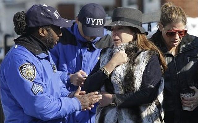 Community affairs police officers speak to women who say they are close friends of the family near the scene of an overnight fire in the Brooklyn borough of New York, Saturday, March 21, 2015. The fire raged through a residence early Saturday, killing seven children and leaving two other people in critical condition, authorities said. (photo credit: AP Photo/Mary Altaffer)