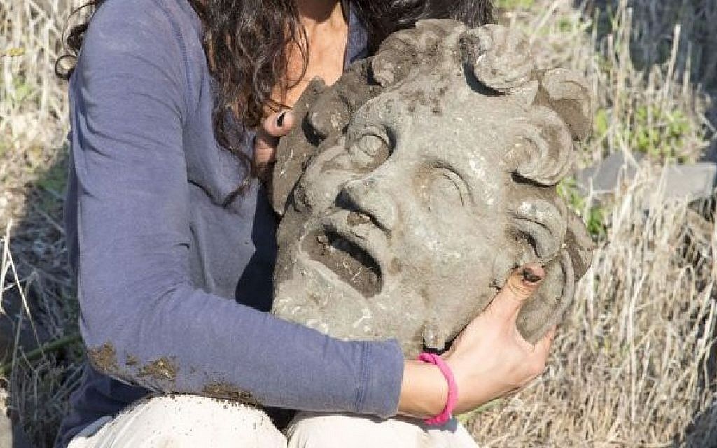 A Haifa University archeologist holding a massive bronze mask of the god Pan, found in early 2015 during digs in teh national park of Susita, in the north of Israel. (photo credit: Courtesy Haifa University)