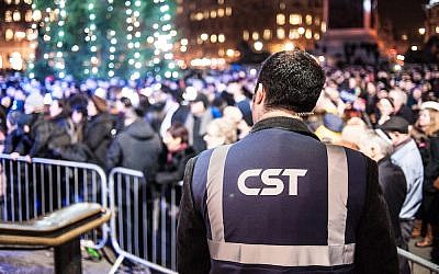 A Community Security Trust guard keeps watch over a Hanukkah celebration in 2014 (Blake Ezra Photography/JTA)